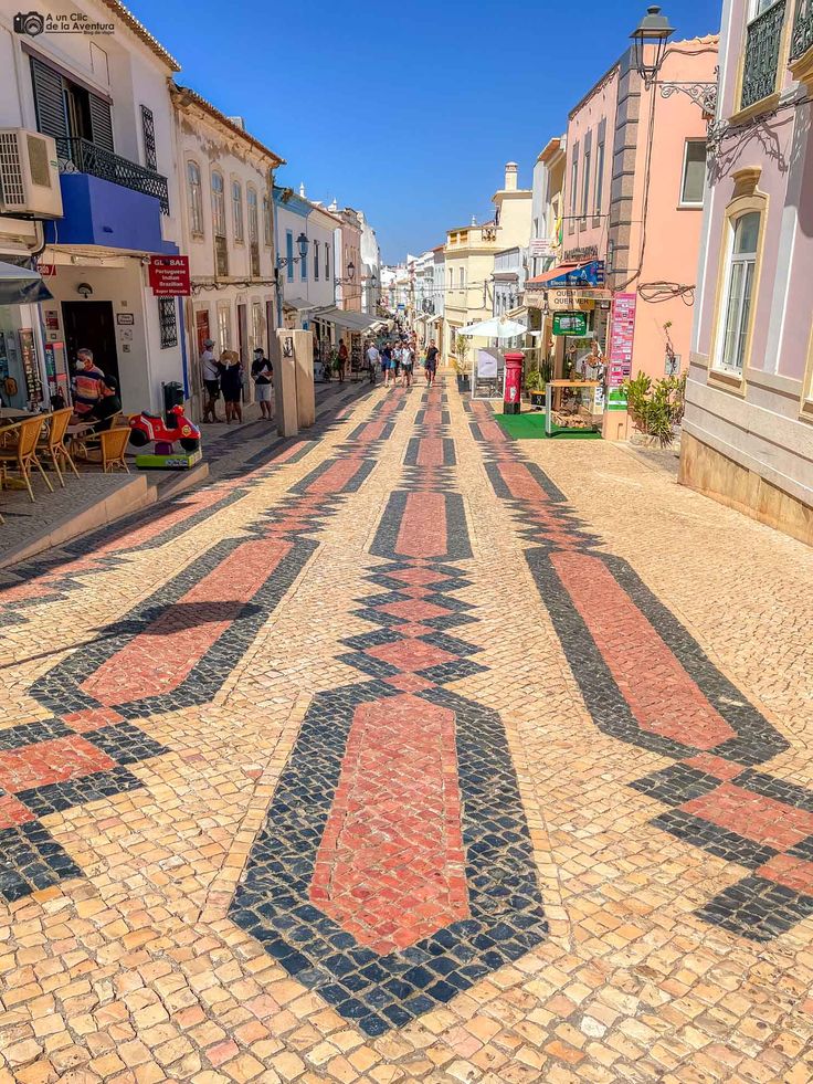 Paved pedestrian street with colorful tiles and shops on either side.